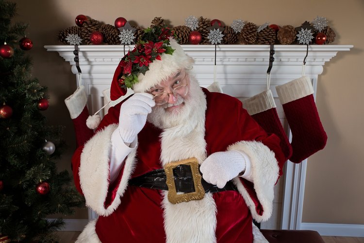 Santa in front of a Christmas tree.