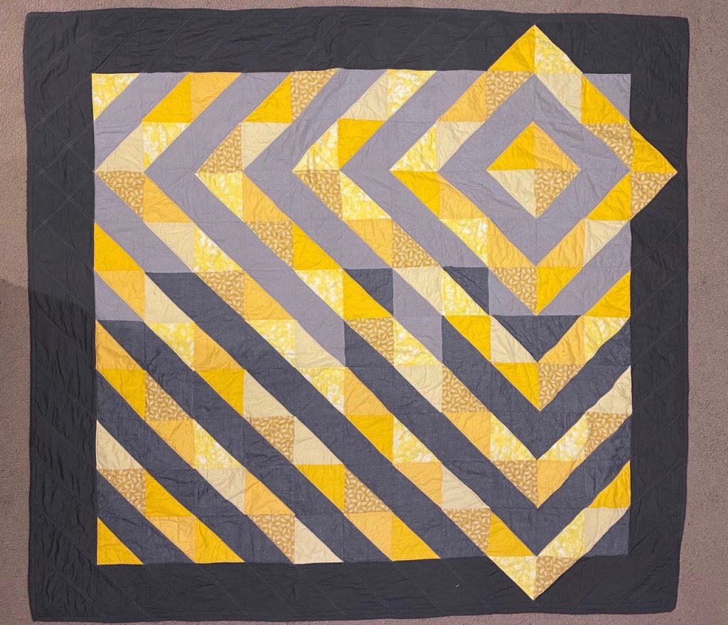 Photo of yellow and grey coloured quilt.