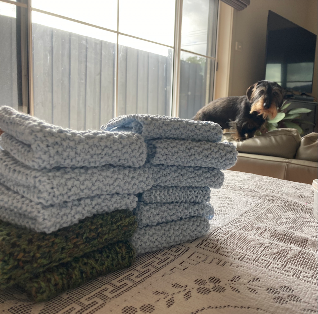 Washcloths piled on a table, with Scout looking on.